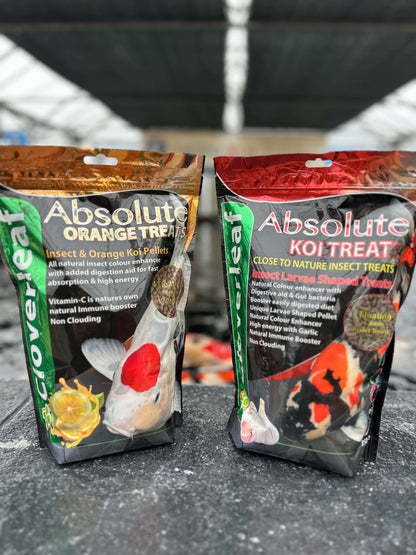 Cloverleaf Koi Treats Insect Larvae Garlic packaging with orange and koi treat varieties in a garden center environment.